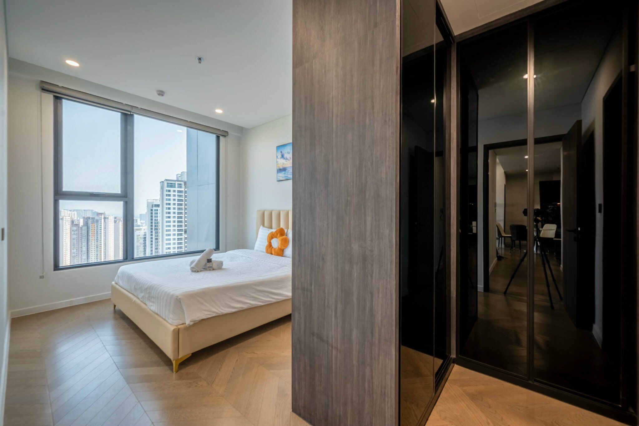 A modern bedroom with a large window, a bed, and a sliding glass door leading to a balcony.