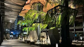 An indoor atrium with hanging greenery, stone planters, and a water feature. - Lumiere Riverside Luxury Apartment (Ho Chi Minh City)