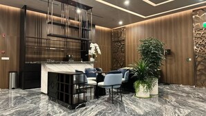 A modern reception area with a marble floor, a reception desk, seating area, and decorative plants. - Lumiere Riverside Luxury Apartment (Ho Chi Minh City)