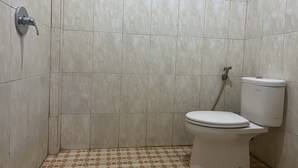 Un baño con inodoro, ducha y paredes con azulejos.