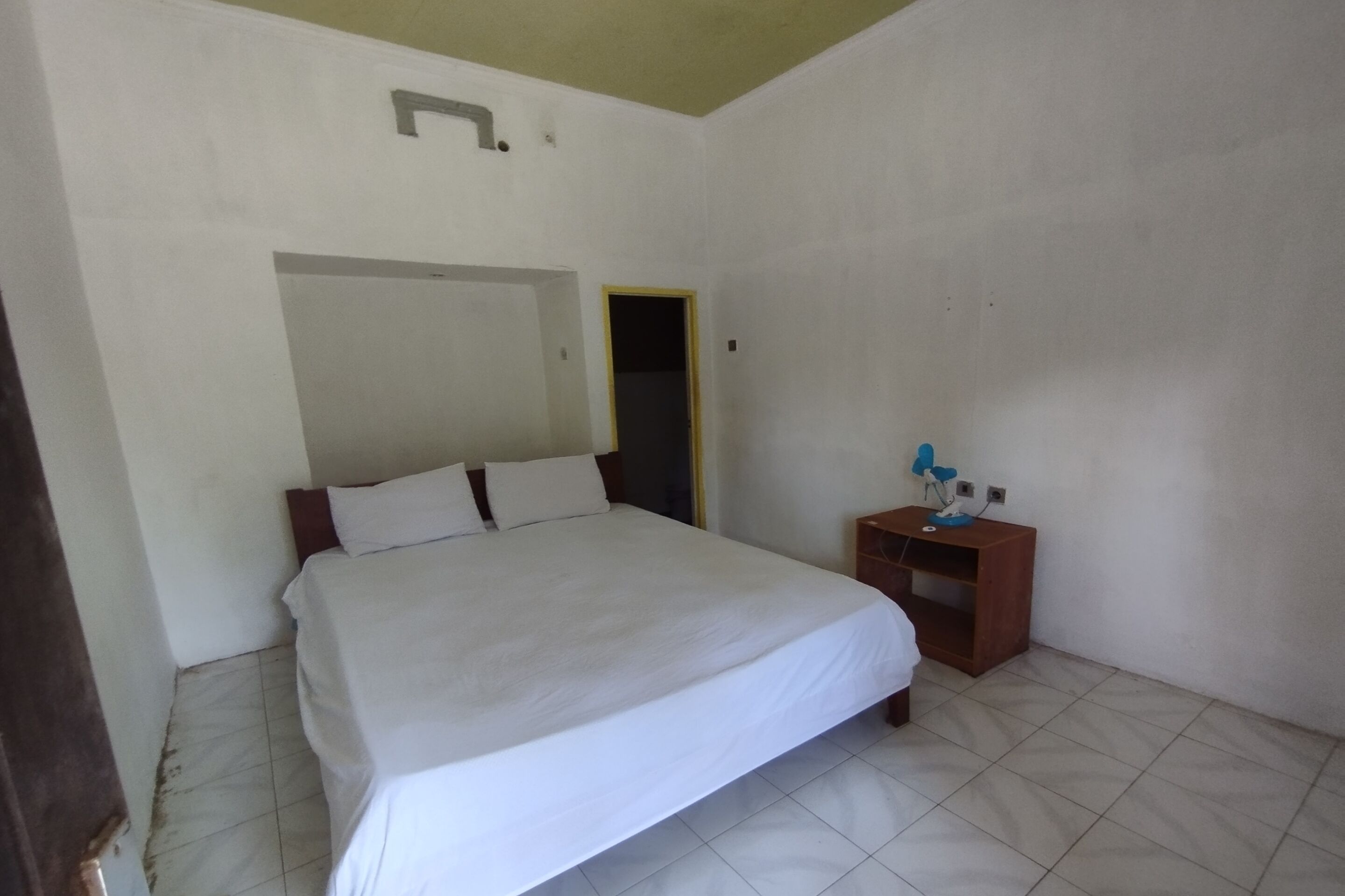 A bedroom with a bed, a nightstand, a door, and a light fixture.