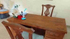 Una mesa de madera para comer con una silla y un pequeño armario.
