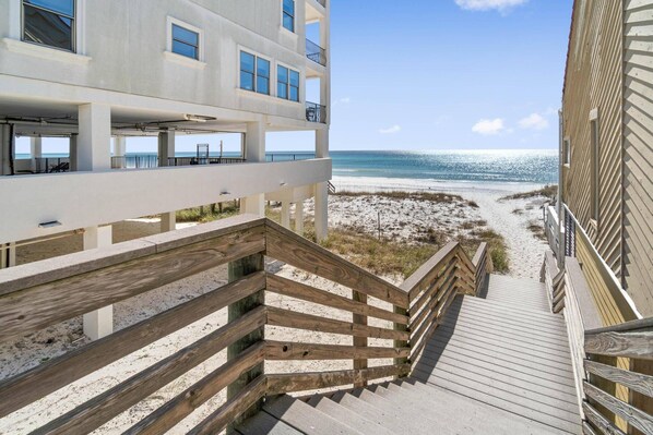 A wooden staircase leading to a beach with a building in the background.
