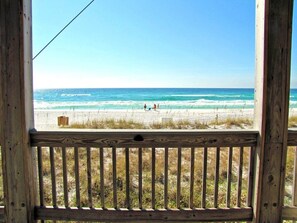 A wooden deck with a view of a beach and ocean.