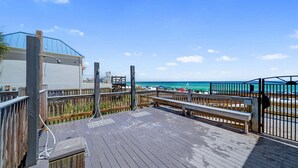 Une terrasse en bois offrant une vue sur la plage et l’océan.