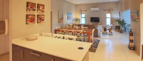 A spacious living area with a dining table, chairs, and a kitchen area with cabinets and a countertop.