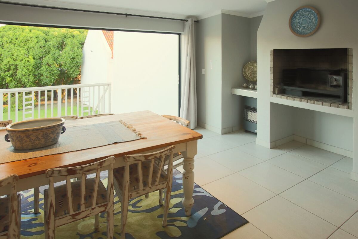A dining area with a wooden table and chairs, a large ceramic bowl, and a patterned rug.