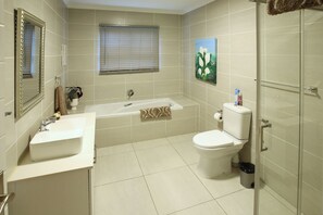 A bathroom with a bathtub, toilet, sink, and a shower area.