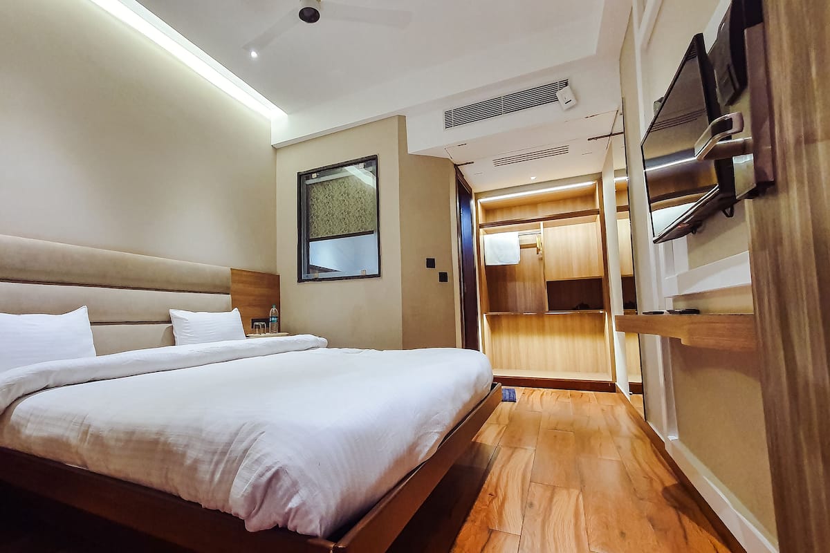 Una habitación de hotel moderna con una cama grande, cabecera de madera y televisor integrado.
