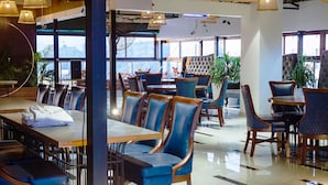 A restaurant with tables and chairs, large windows, and plants.