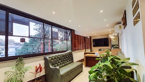 A modern reception area with a sofa, a reception desk, a large window, and a television.
