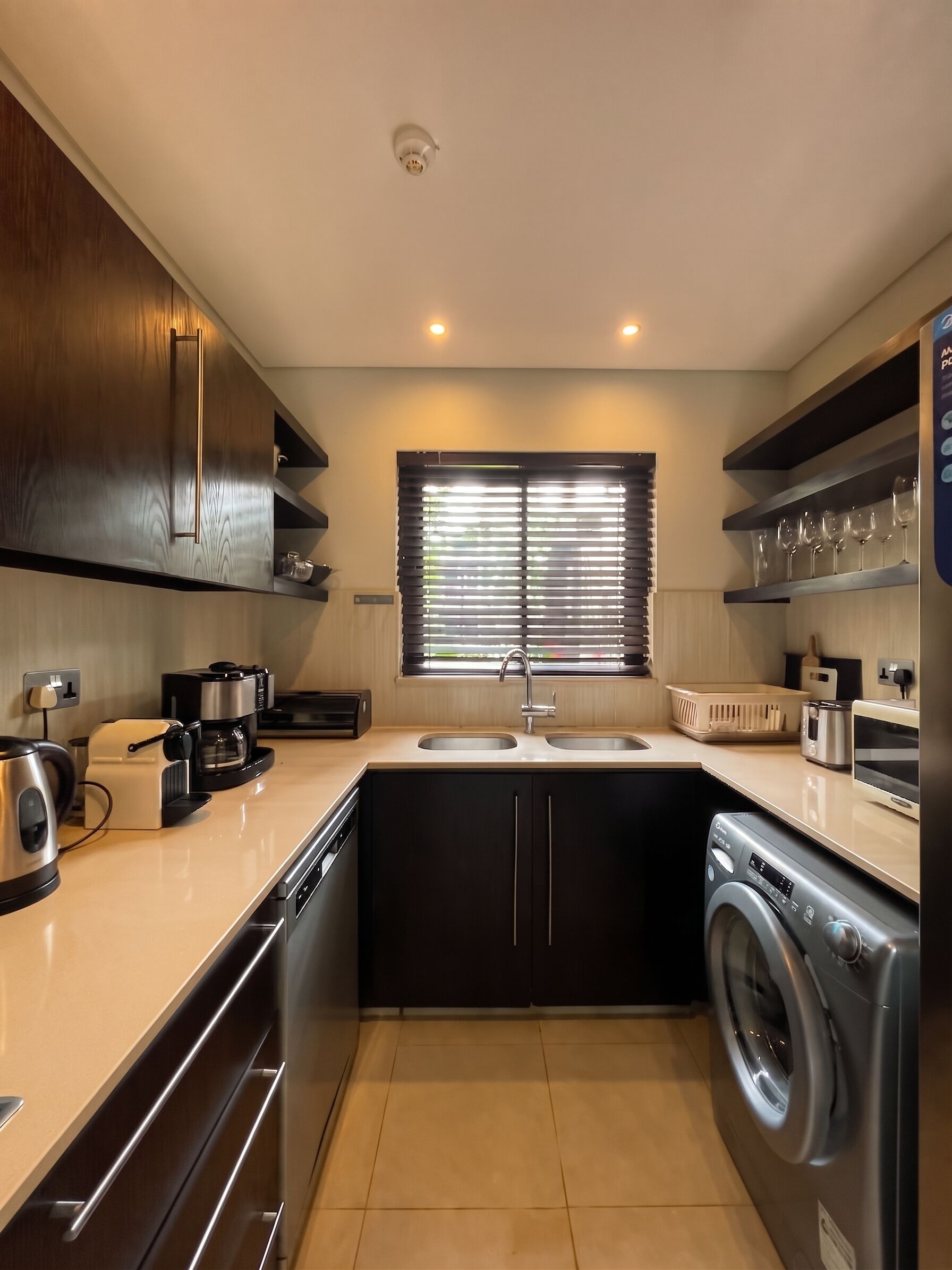 A compact kitchen with a dishwasher, a coffee machine, a microwave, a sink, and a built-in washing machine.