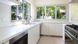 Une cuisine moderne avec des meubles blancs, un évier en acier inoxydable et une cuisinière à gaz.