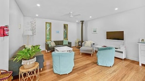 A modern living room with a sofa, two armchairs, a coffee table, a fireplace, and a television. - Aireys Bush Retreat - Spacious home with huge deck (Aireys Inlet)