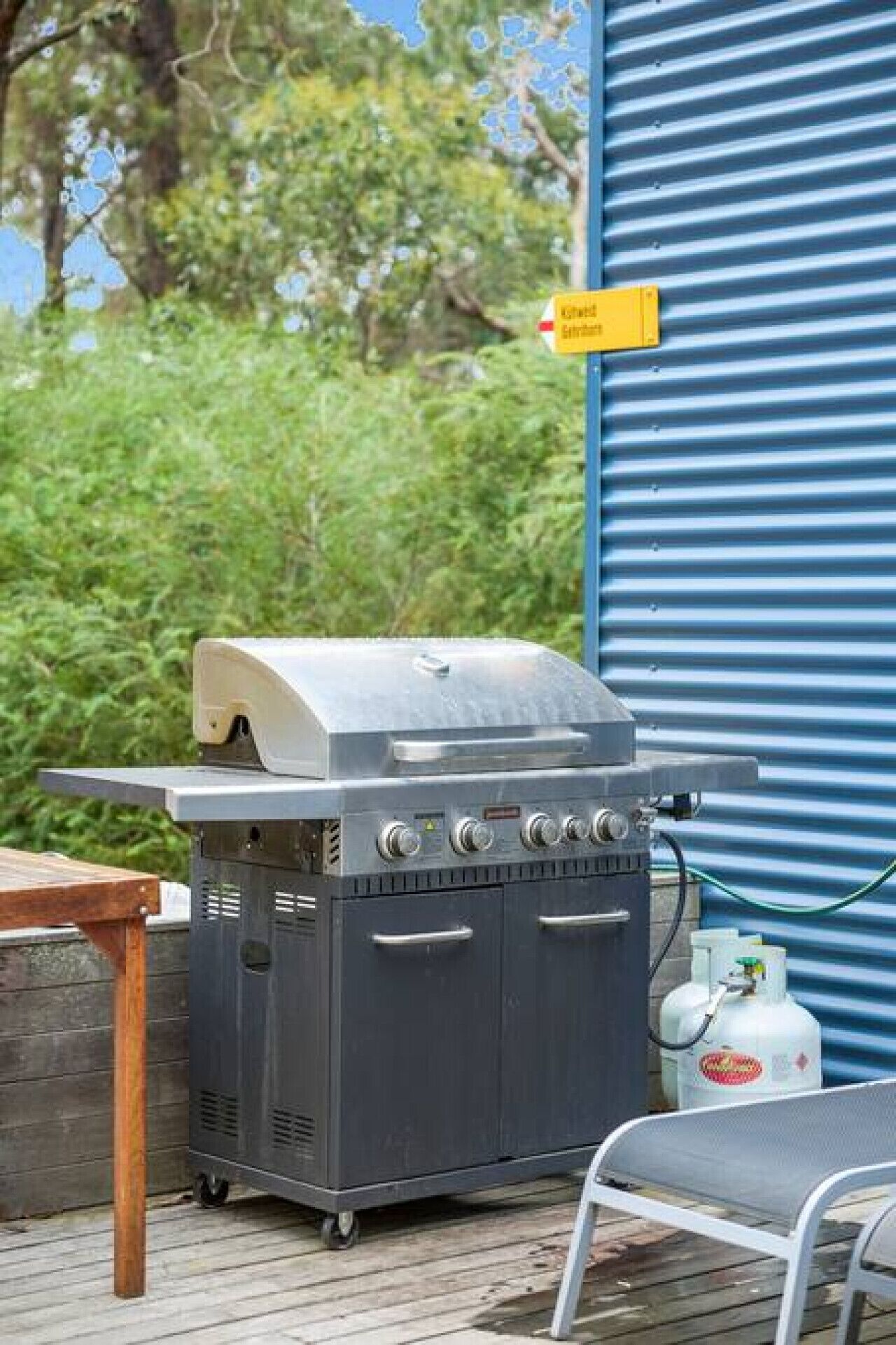 A charcoal grill with a chimney, a gas tank, and a hose.