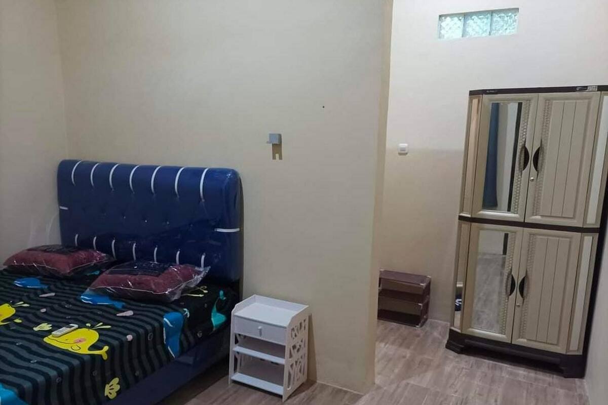 A bedroom with a bed, a wardrobe, a small table, and a window.