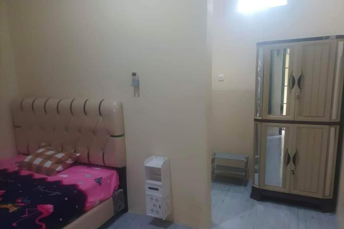 A bedroom with a bed, wardrobe, and a small cabinet.