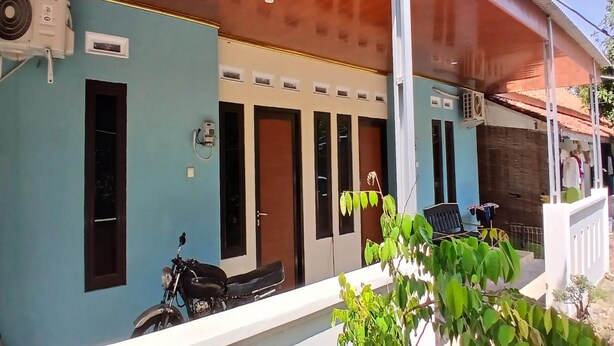 A building with a blue exterior, multiple doors, and a covered porch area. - Hotel O Ayna Kost Syariah (Singaraja)