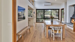 Un comedor amplio con una gran mesa y sillas, un banco y una chimenea.