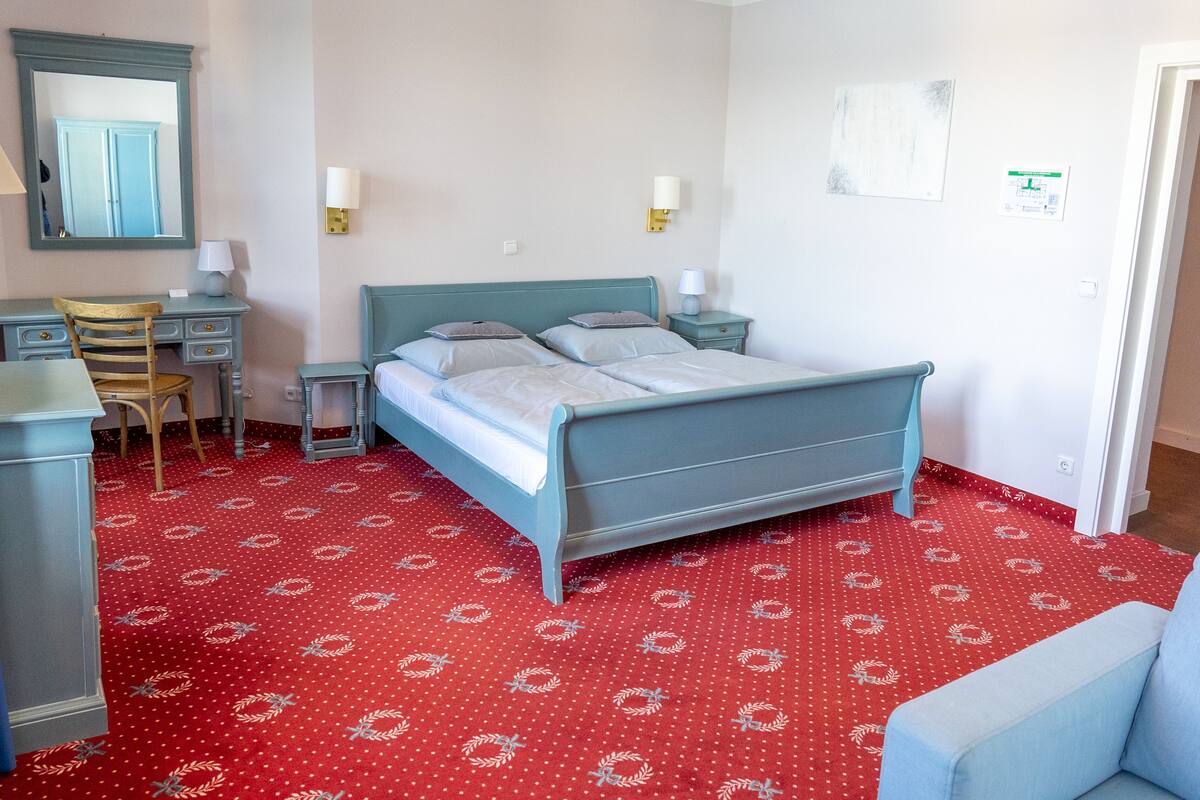 A hotel room with a bed, a desk, a chair, and a small table.