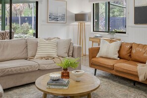 A living room with two sofas, a coffee table, a floor lamp, and a painting on the wall. - Sunnymead Heated Pool Retreat (Aireys Inlet)