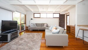 A modern living room with a flat-screen TV, grey sofas, and a wooden floor. - Bush Serenity  - Anglesea (Anglesea)