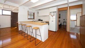 A spacious kitchen with a central island, bar stools, and a refrigerator. - Bush Serenity  - Anglesea (Anglesea)