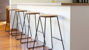A modern kitchen with a white island, wooden bar stools, and a window with a hanging light fixture. - Bush Serenity  - Anglesea (Anglesea)