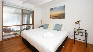 A modern bedroom with a large bed, a view of the outdoors through a sliding glass door, and a painting on the wall. - Bush Serenity  - Anglesea (Anglesea)