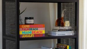A black, semi-open shelving unit with books, decorative items, and a small plant.