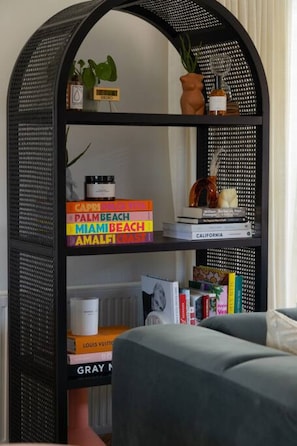 A black, semi-open shelving unit with books, decorative items, and a small plant.