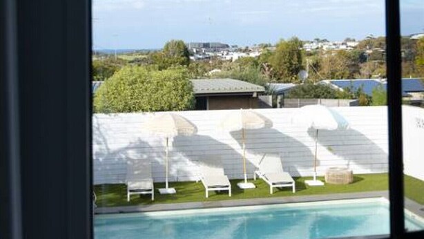 A view of a swimming pool with lounge chairs and a building in the background.