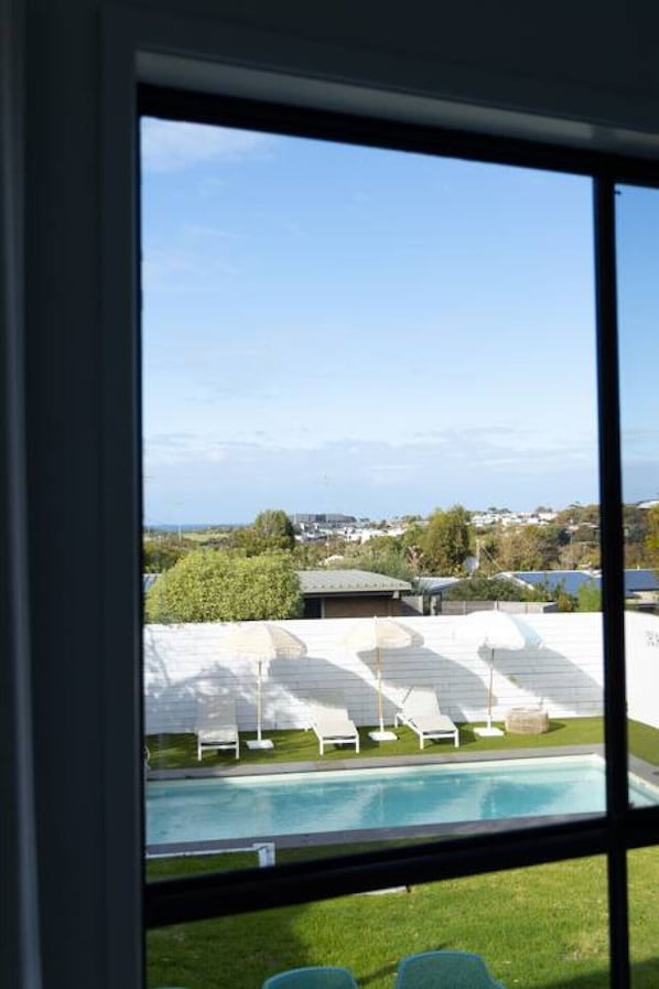 A view of a swimming pool with lounge chairs and a building in the background.