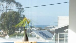 A dining area with a table and chairs, a vase with flowers, and a view of a residential area with solar panels.