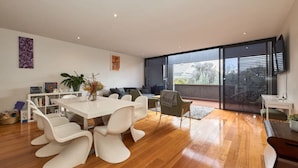 A modern living room with a dining area, large windows, and a view of the outdoors.