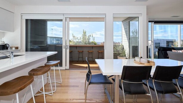 Una cocina moderna con una isla grande, taburetes de bar y un comedor con sillas.