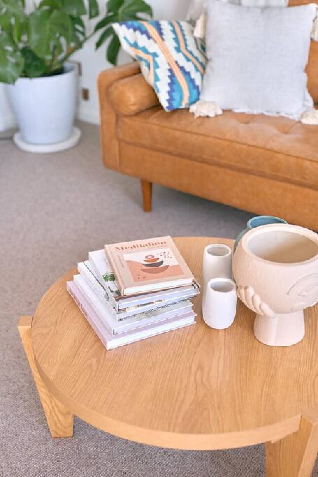 Taula de fusta rodona amb un grapat de llibres, dues tasses de ceràmica blanca i una mug de ceràmica.
