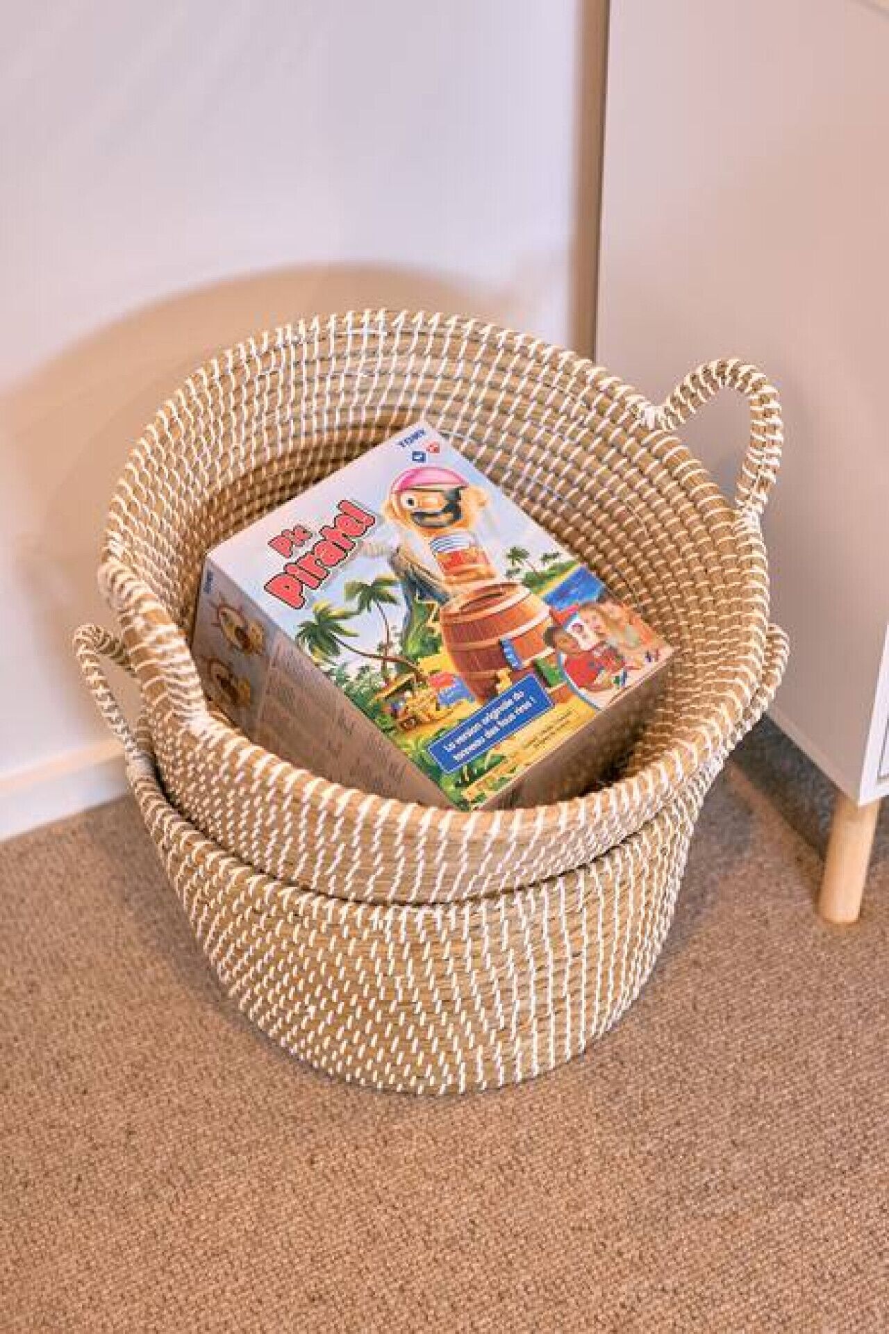 A woven basket with handles containing a box.