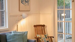 Una sala de estar acogedora con un sofá azul, una silla de madera y una obra de arte enmarcada en la pared.