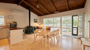 Una cocina amplia con pisos de madera, un comedor con mesa y sillas, un ventanal y vistas al exterior.