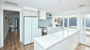 Una cocina moderna con armarios blancos, una isla central y vistas al patio trasero.