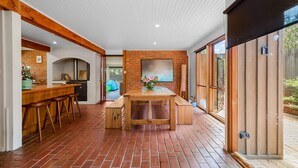 Una cocina amplia con suelo de ladrillo, taburetes de madera y una isla central.