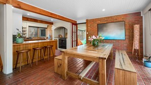 Una cocina amplia con barra de madera, taburetes y suelo de ladrillo.