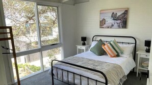 A bedroom with a bed, a window, a painting, and a ladder. - Eagles Nest (Aireys Inlet)