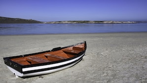 A small boat on a sandy beach with calm water and a clear sky. - Oppi Stuppi Langebaan 4-Sleeper (Langebaan)