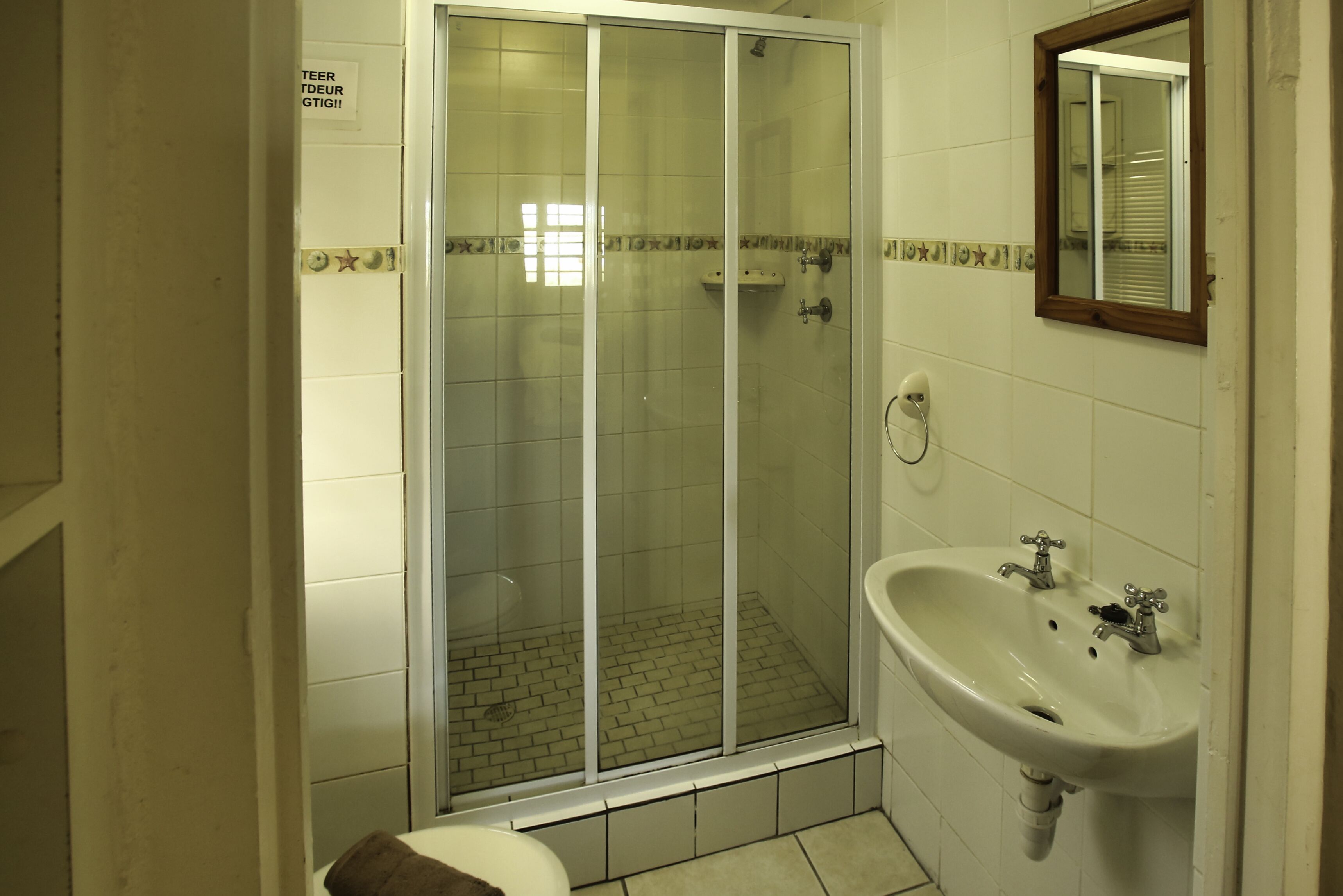 A bathroom with a glass-enclosed shower, a sink, and a mirror.