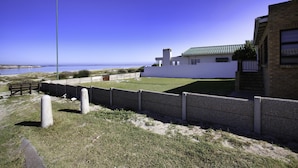 A modern building with a green roof, a fenced yard, and a clear view of the ocean. - Oppi Stuppi Langebaan 4-Sleeper (Langebaan)