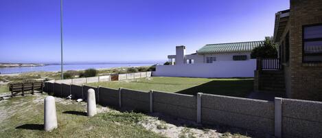 A modern building with a green roof, a fenced yard, and a clear view of the ocean.