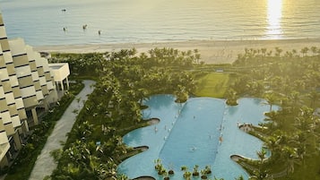 Relax by the pool surrounded by lush greenery and palm trees, with access to a pristine beach.