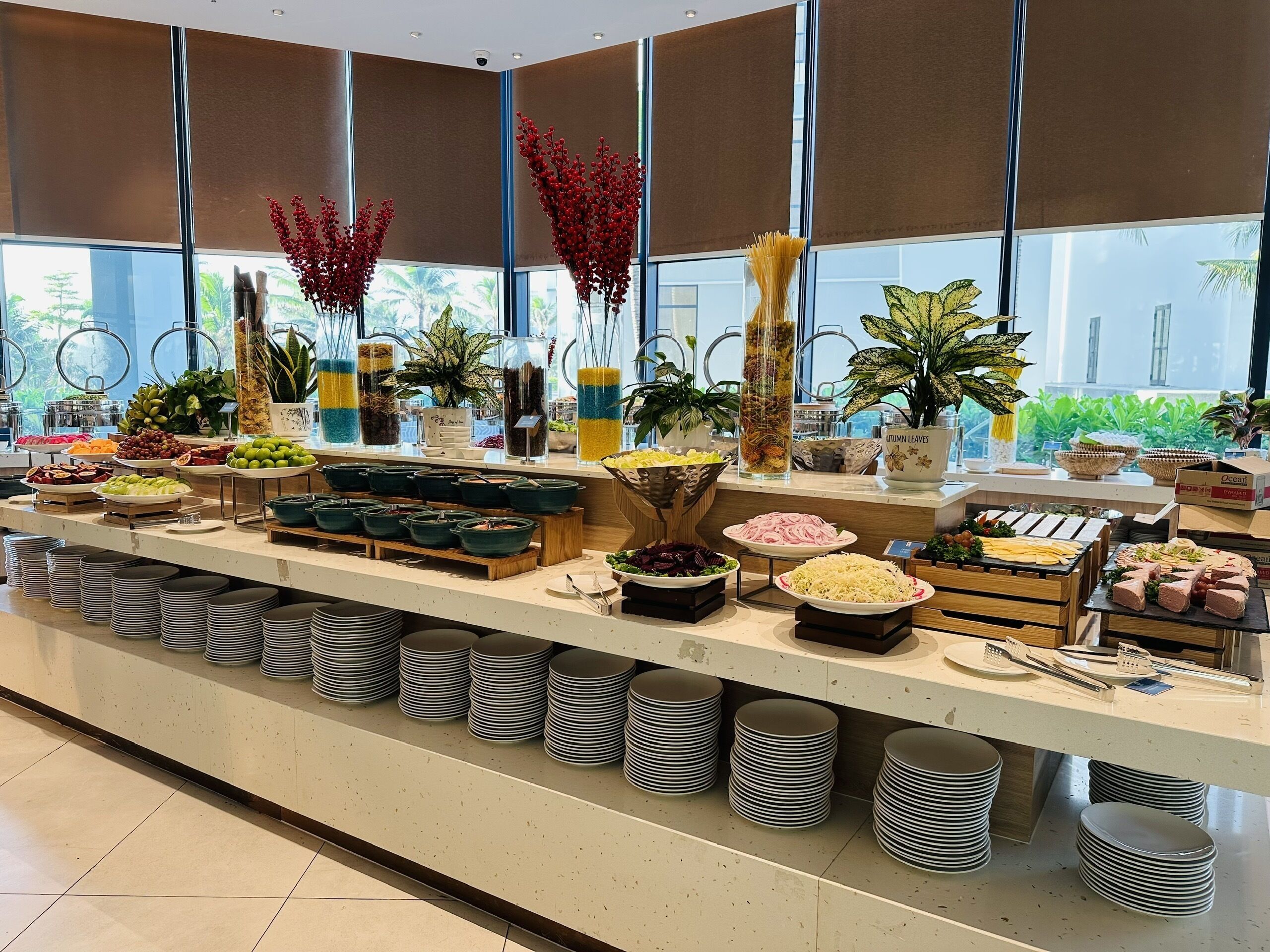 A buffet setup with various food items and decorative plants.
